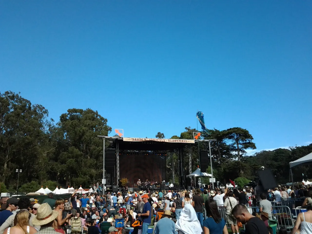 A crowd sitting on the grass in front of a stage at Hardly Strictly Bluegrass