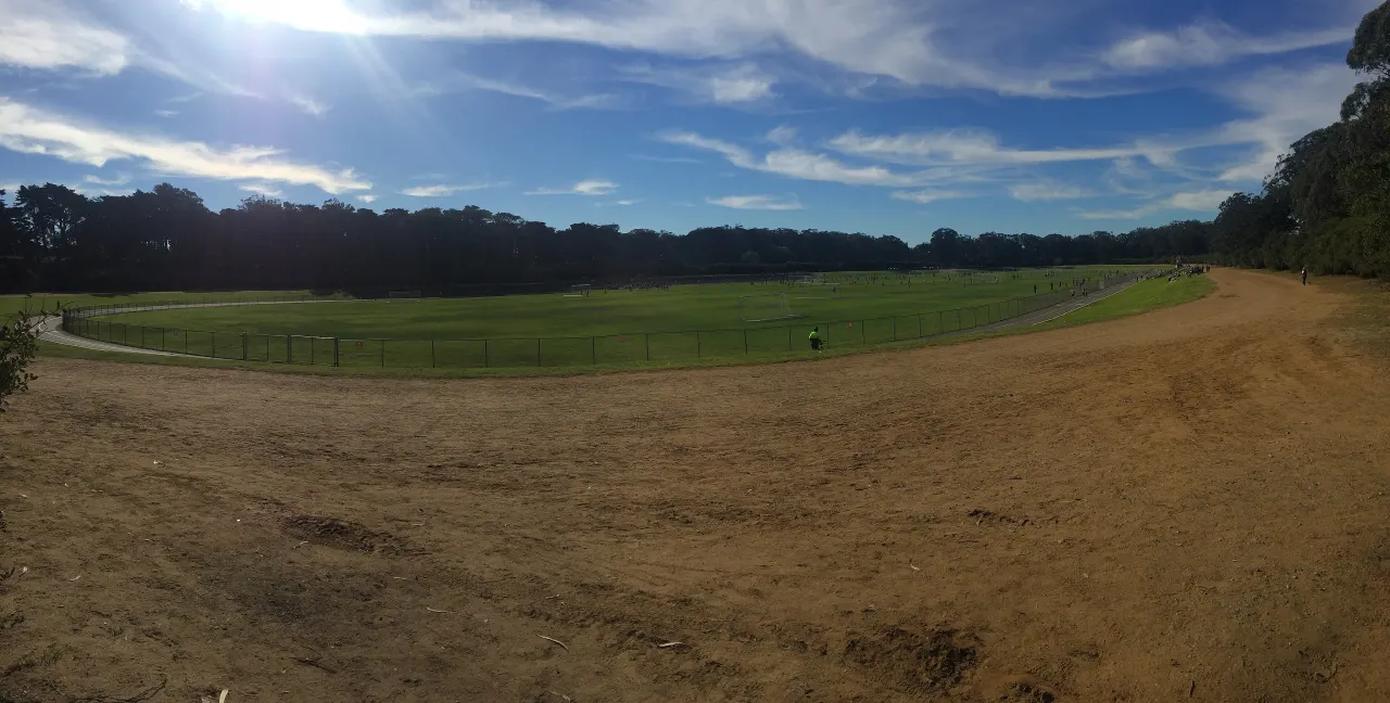 The wide green Polo Field and its running track surrounded by trees